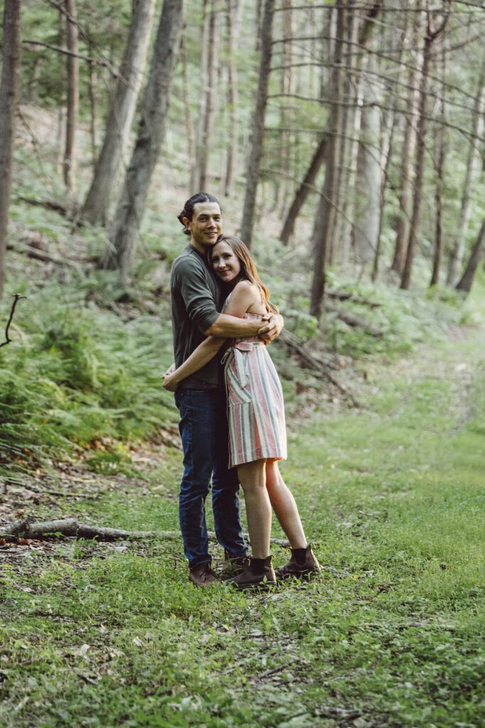 A couple embraces during an engagement session in the woods of Pennsylvania