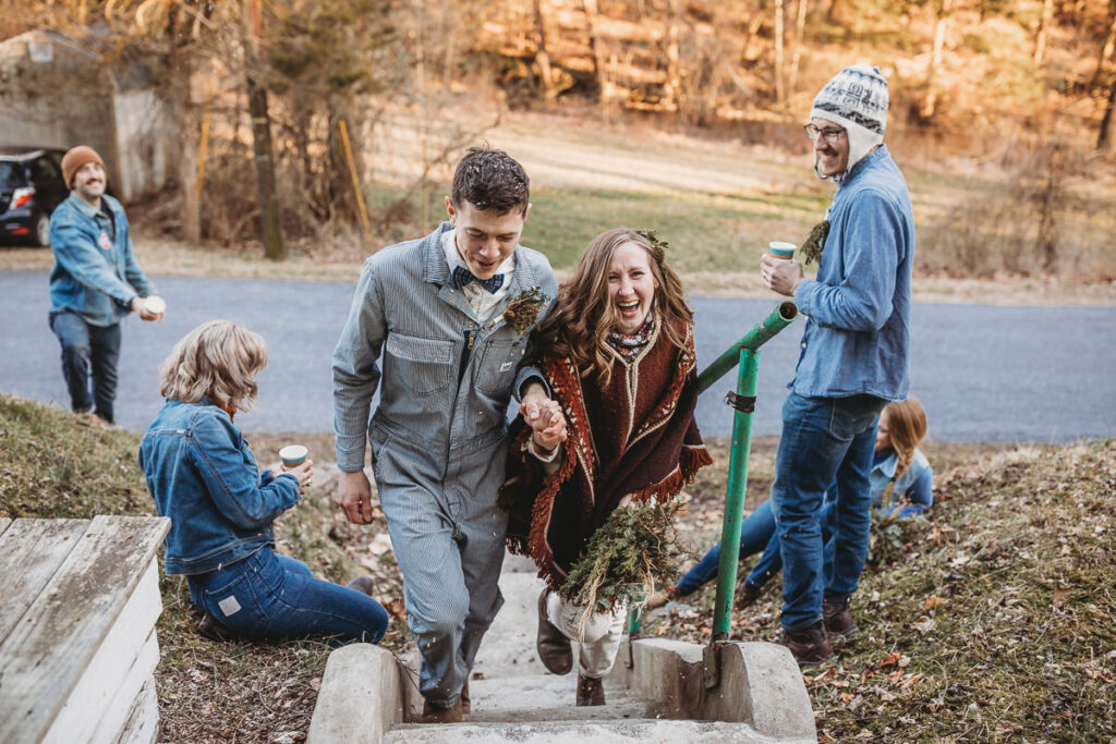 A couple climbs up the outside stairs at their home, while their friends throw bird seed at them. They are all wearing denim