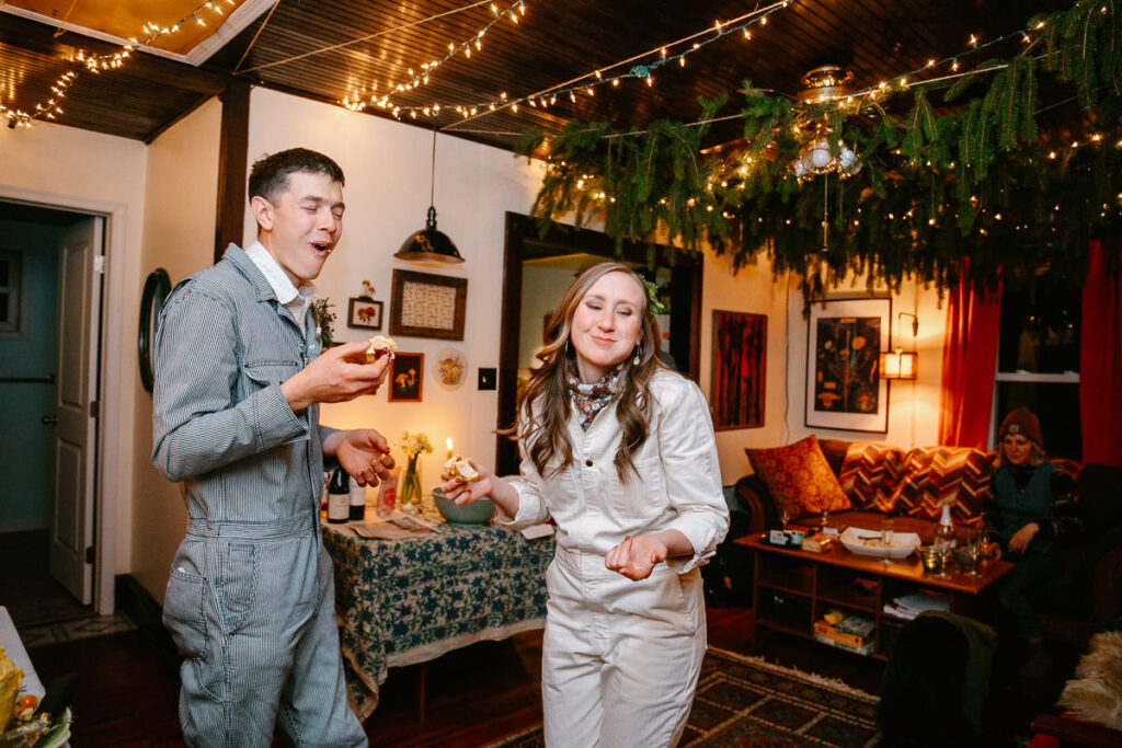 A bride and groom afterf eeding each other cake during their intimate reception inside their home. They both are making a face like the cake is delicious. 