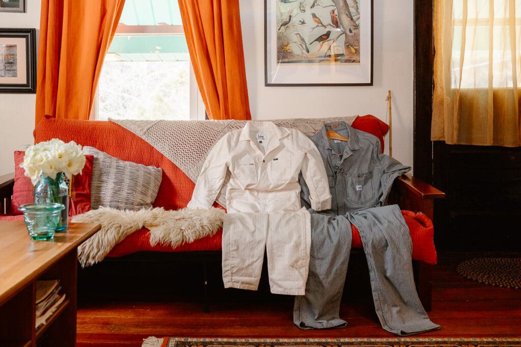 A detail photo of the Lee jumpsuits that the couple were wearing for their wedding day sitting on a couch. 