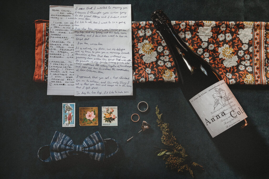 Details from an elopement day. The vows, bowtie, rings, handkerchief, and a custom bottle of wine with their names on it.