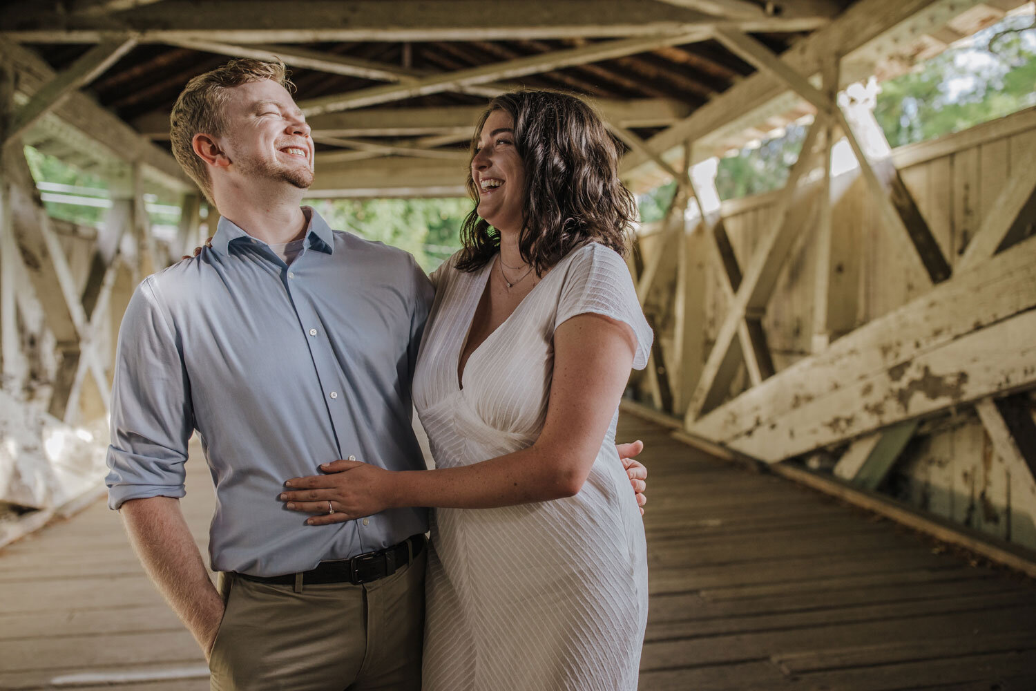 a couple posing inside of a covered bridge