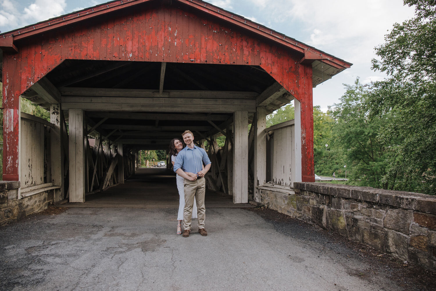 engaged couple posing in front of a covered bridge