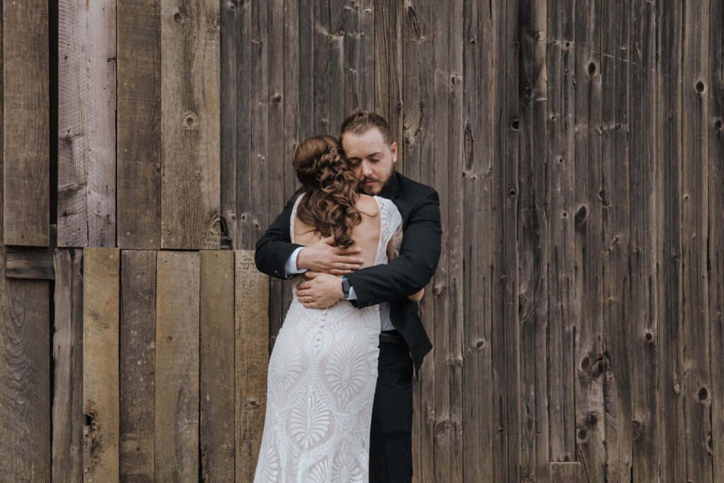 A couple embraces in front of a wooden barn door during their micro wedding in the Lehigh Valley