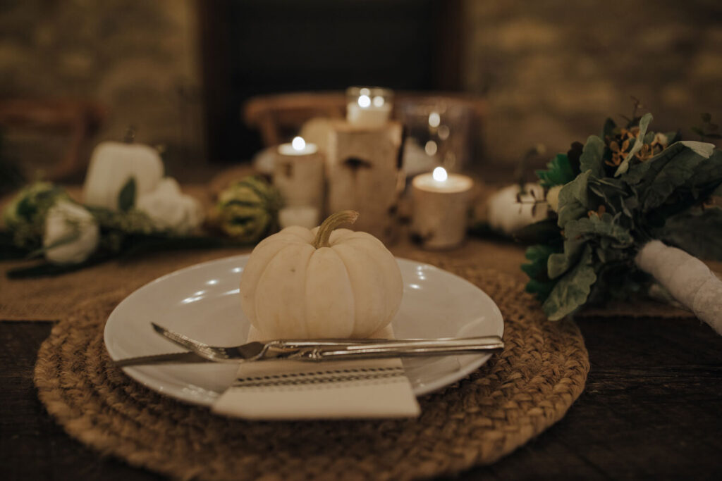 A beautiful table setting for a brunch micro wedding in the lehigh valley. There are white pumpkins, candles, and greens