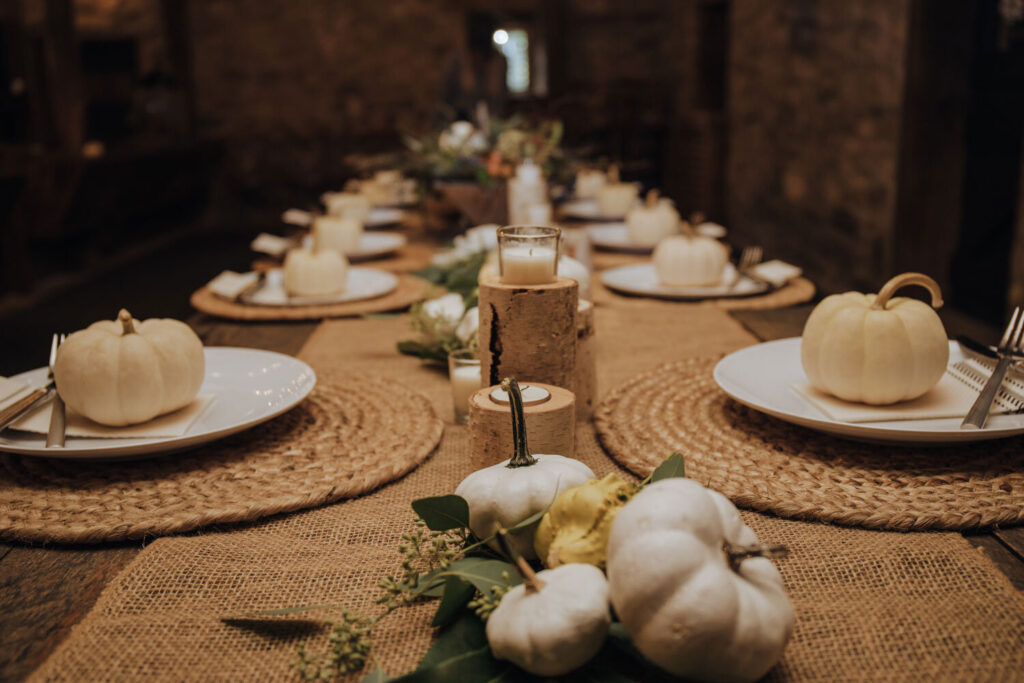 A fall tablescape from a micro wedding, including white pumpkins, candles, and place settings