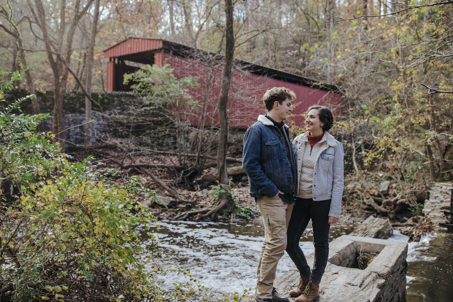 A couple posing in front of a covered bridge at Wissahickon Park