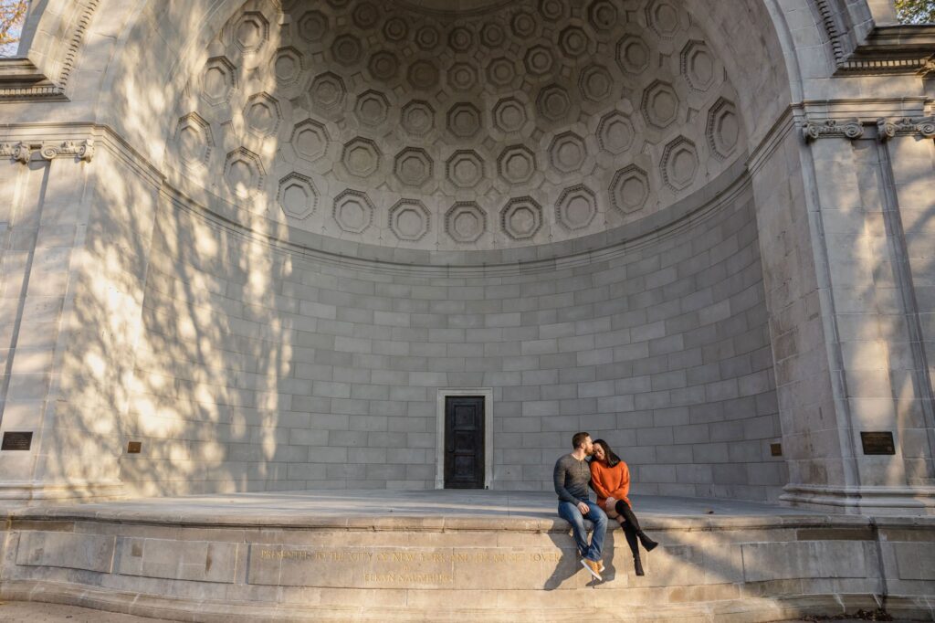 A couple sit on the Naumberg Stage in New York City. The woman is leaning in while the man kisses her forehead