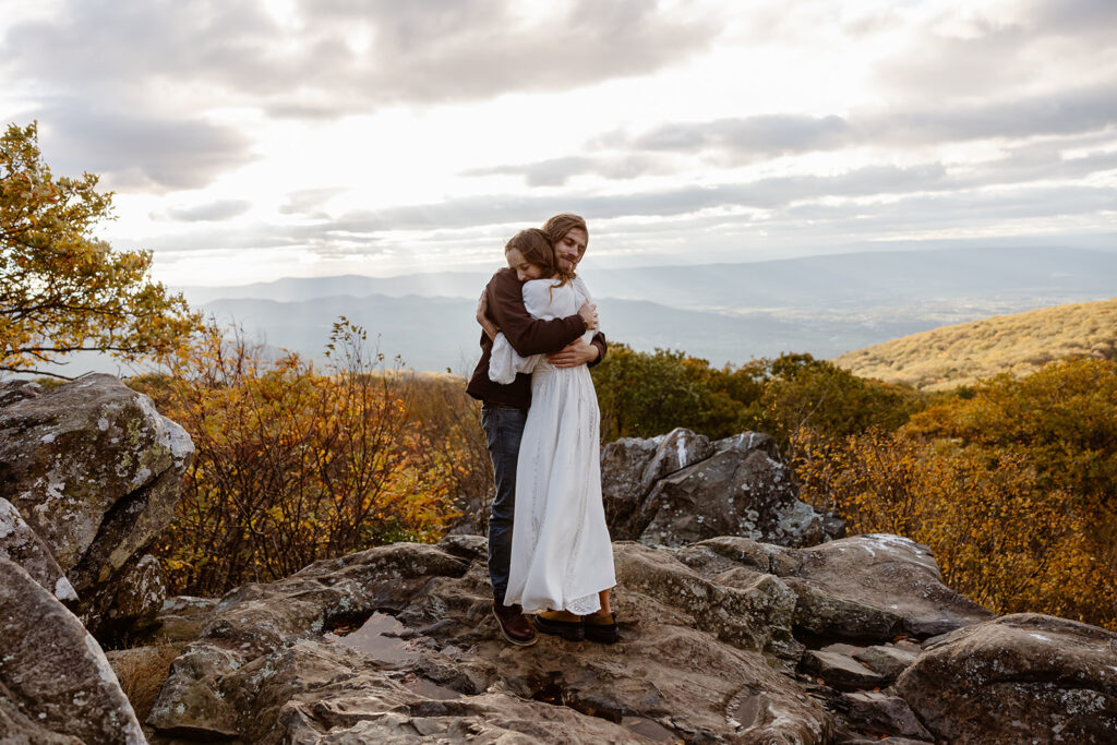 A bride and groom embrace on Hawksbill Mountain. The wind was howling so they are holding each other tightly. Shenandoah National Park Elopement