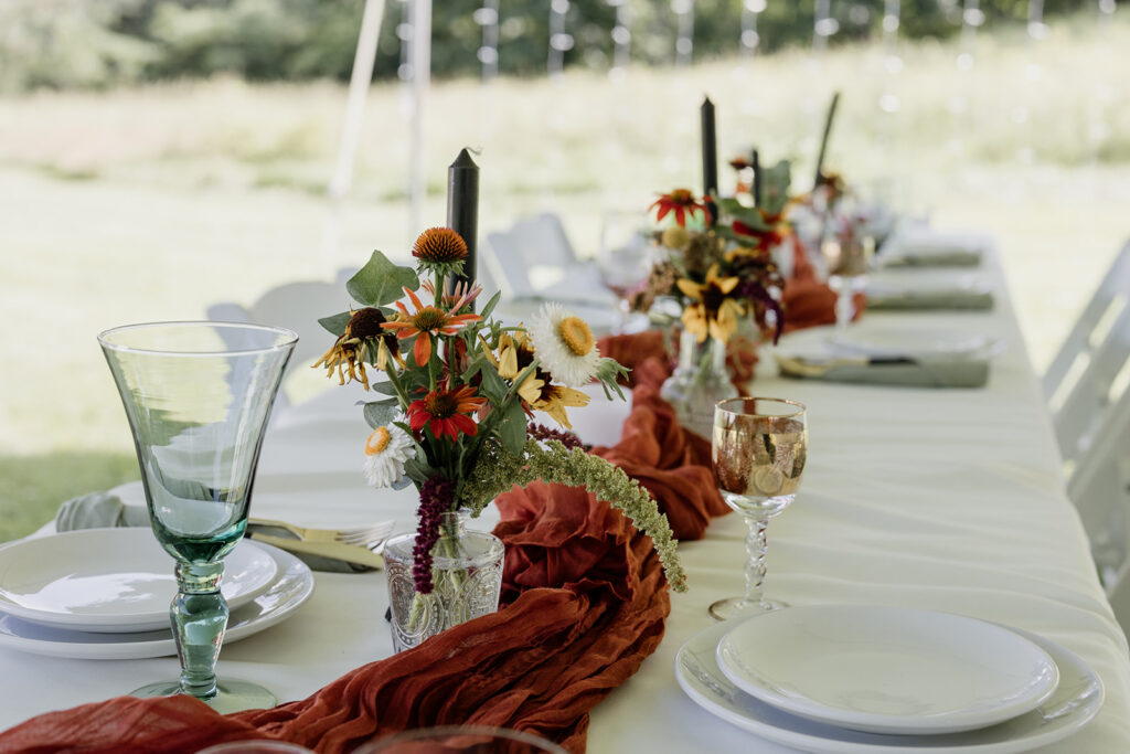 A detail photo of the tables at the reception. They have antique glassware, candles, and wildflowers. 