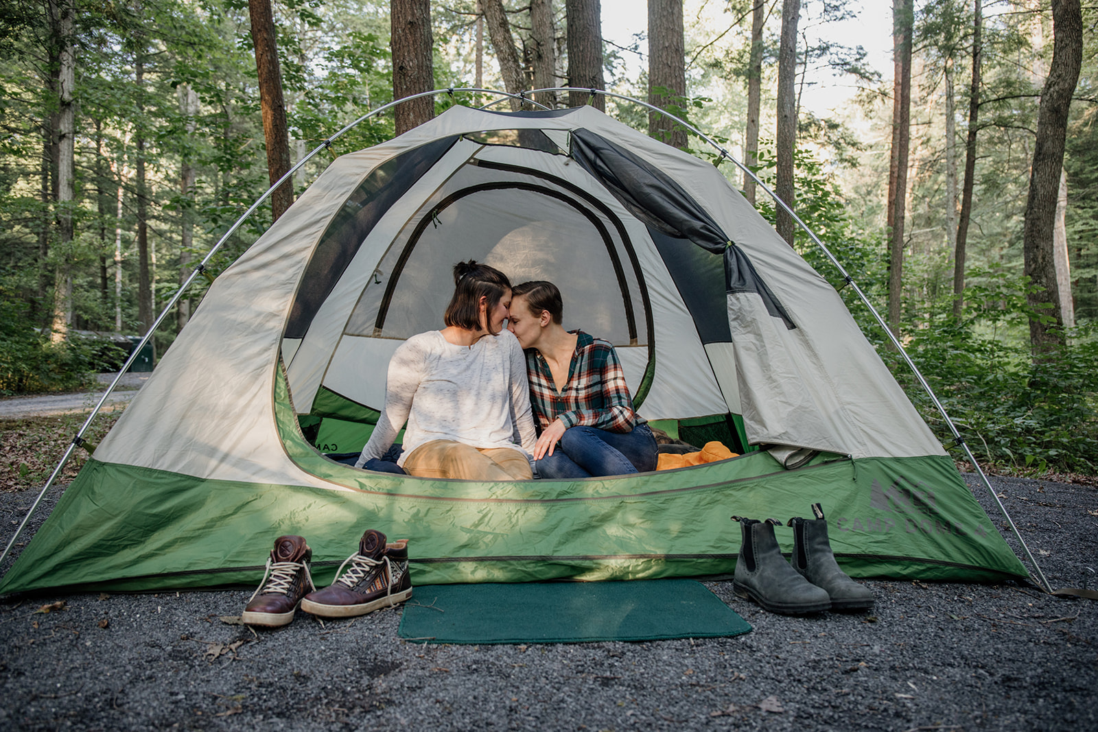 same sex couple snuggling in a tent at thier engagement session