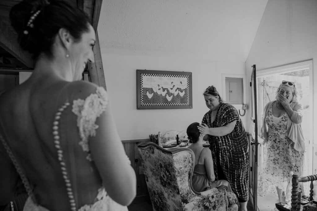 The mother of the bride sees the bride for the first time. The photo is in black and white. The mother has her hand over her mouth with emotion.