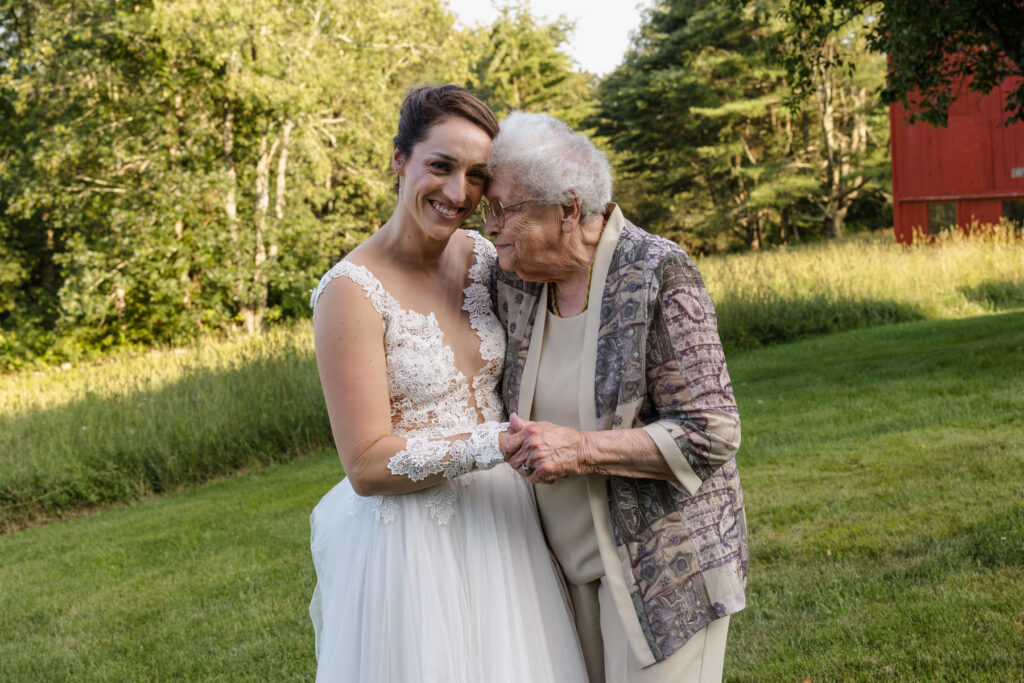 A bride and her grandmother share a sweet moment. They are holding hands, and their foreheads are touching