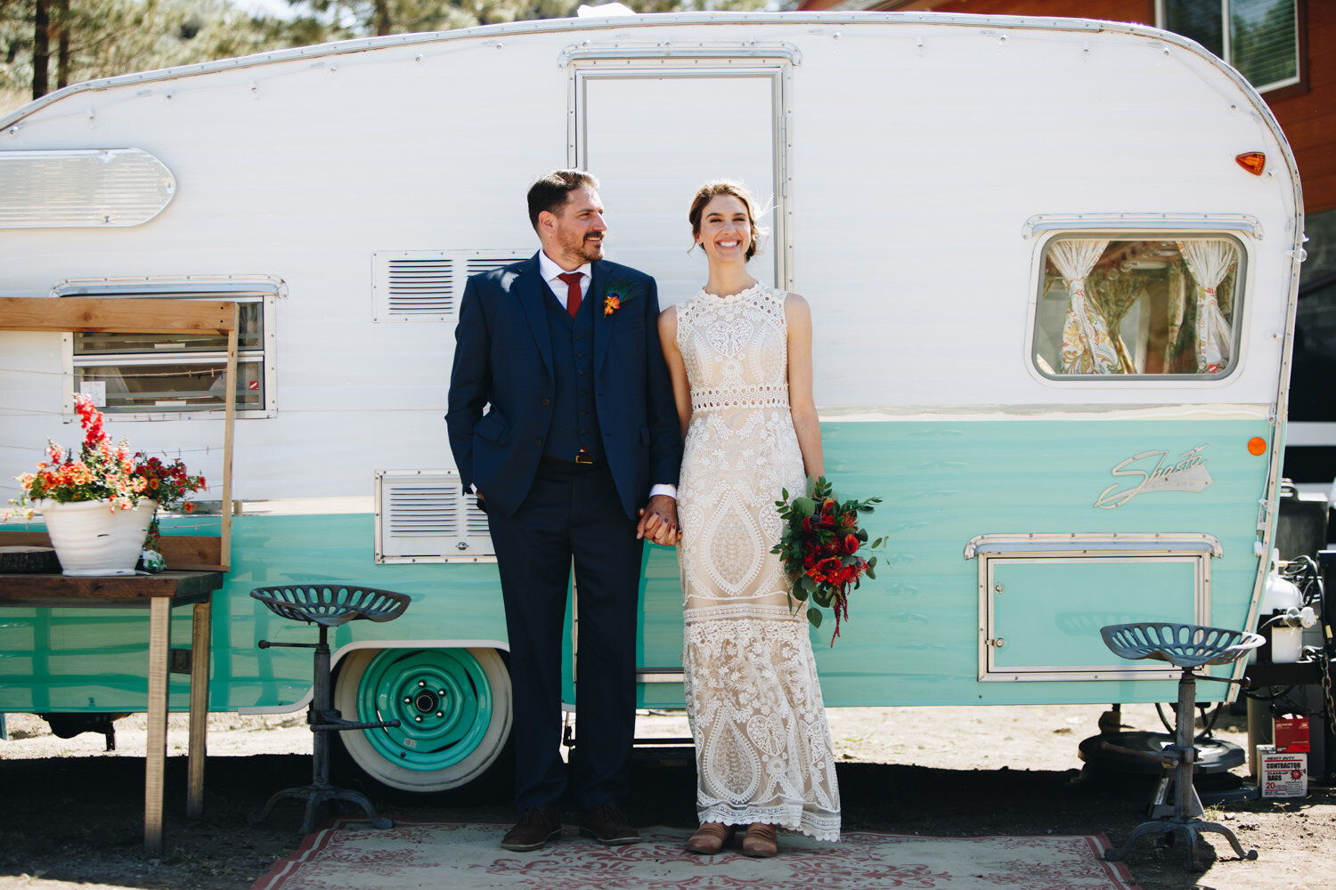 Bride and Groom standing in front of their camper on their wedding day