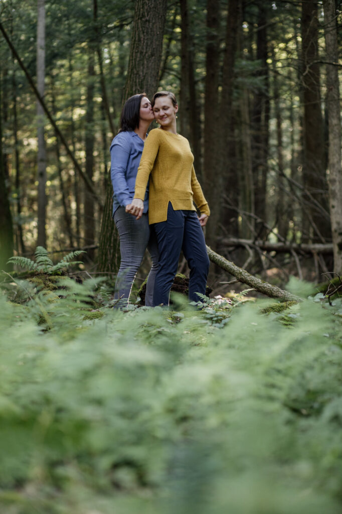 A couple holding hands in the forest during their engagement session