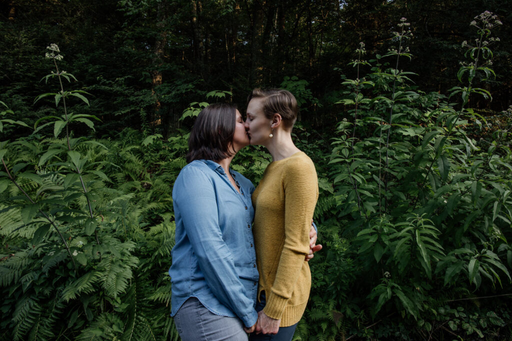 same sex couple kissing amidst some luscious foliage