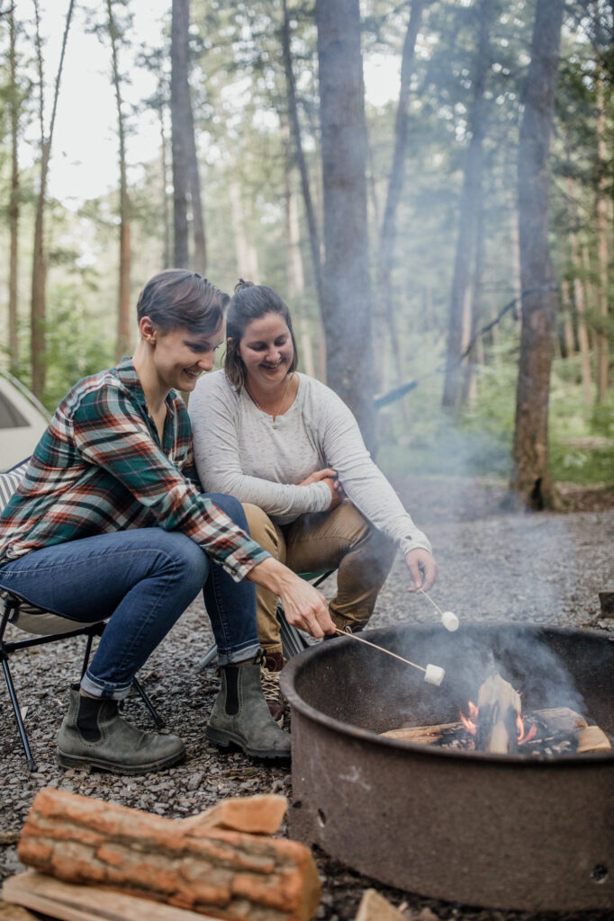 same sex couple roasting marshmallows by the fire during their engagement session