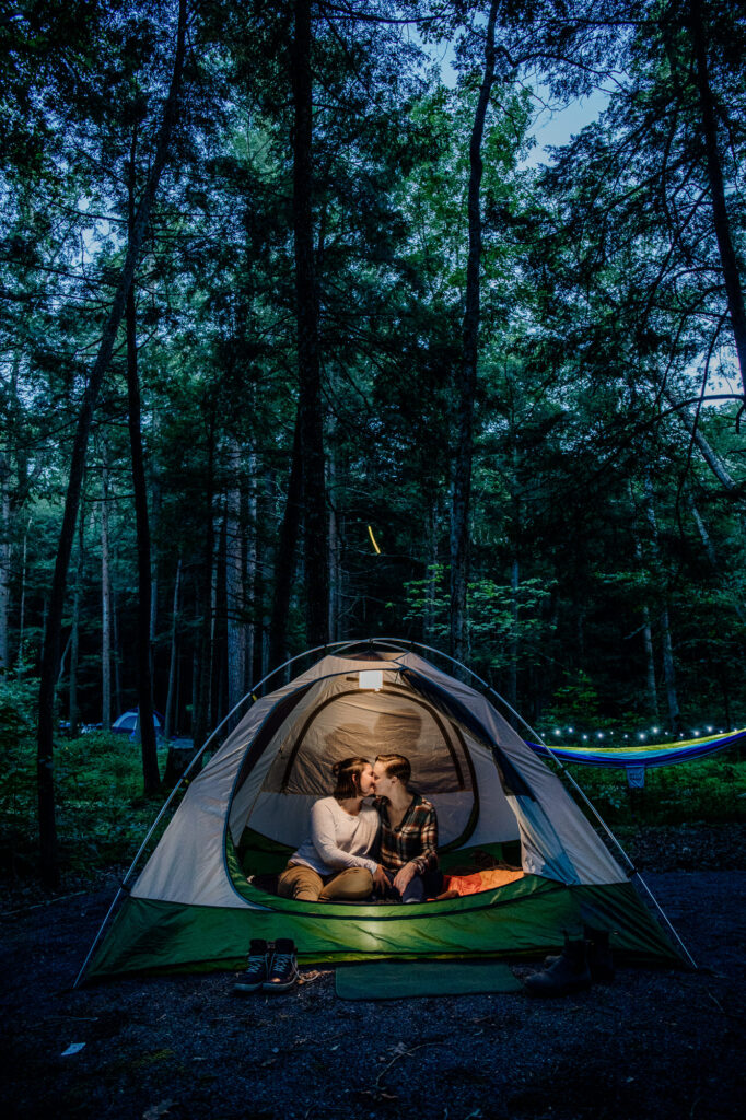 couple kissing in a tent at dusk during their engagement shoot
