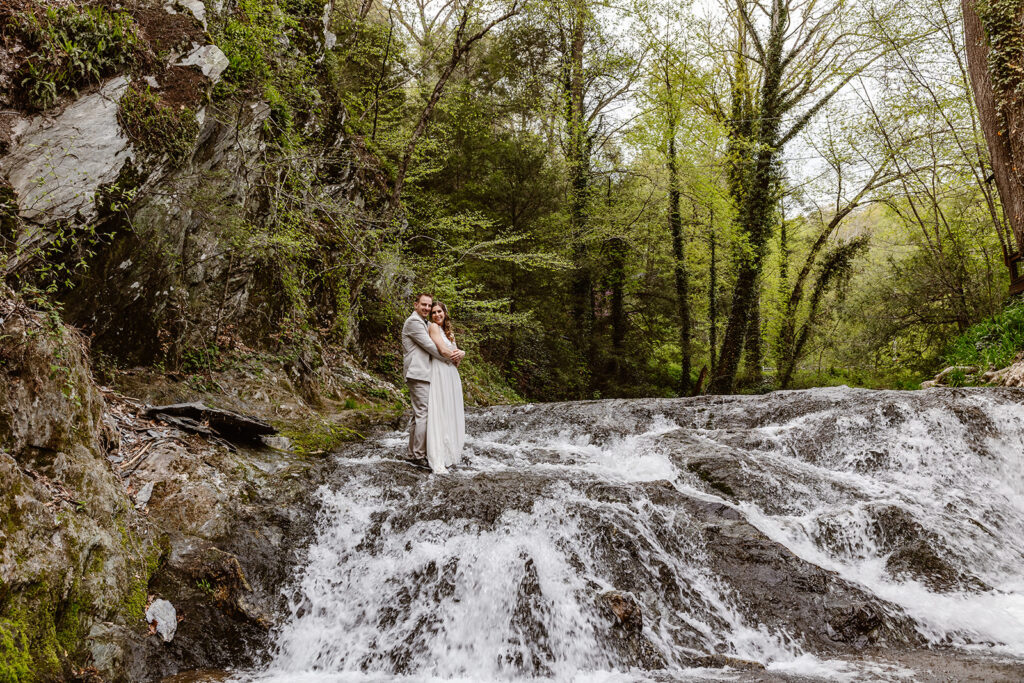 An couple embracing  while standing in a waterfall during their Pennsylvania elopement. 