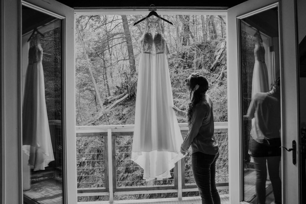 bride admiring her hanging dress before getting dressed on her wedding day