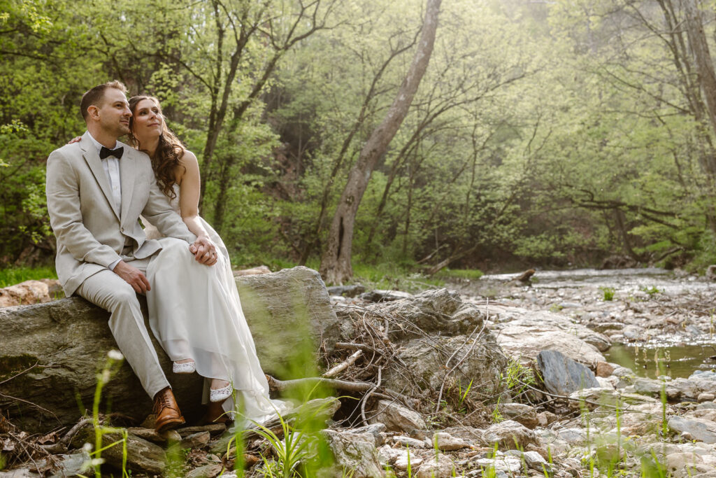 Couple sitting on a log by a waterfall during their elopement day