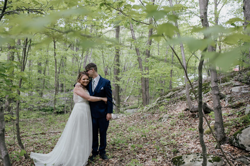 A couple hugging and smiling in the woods 
