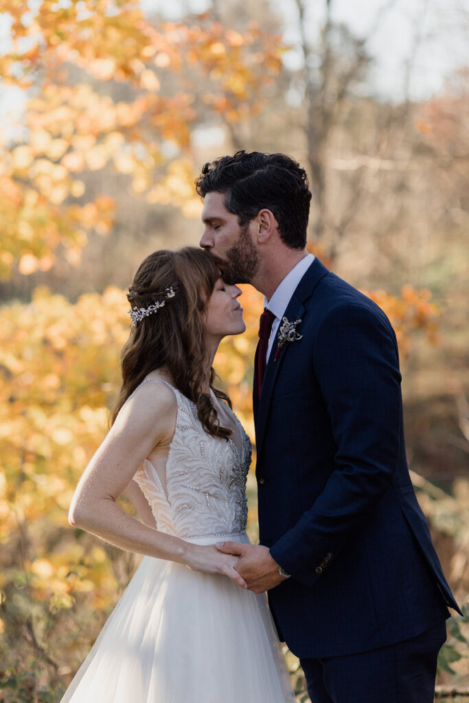 A person kissing their partner on the forehead. 
