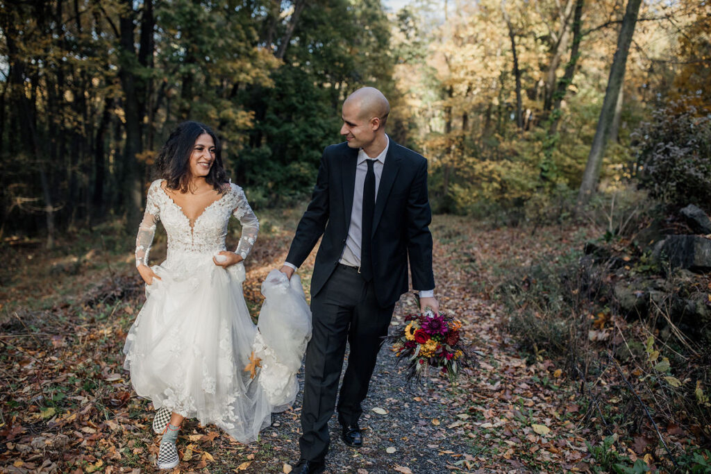 A person holding their partner's train as they walk in the woods 
