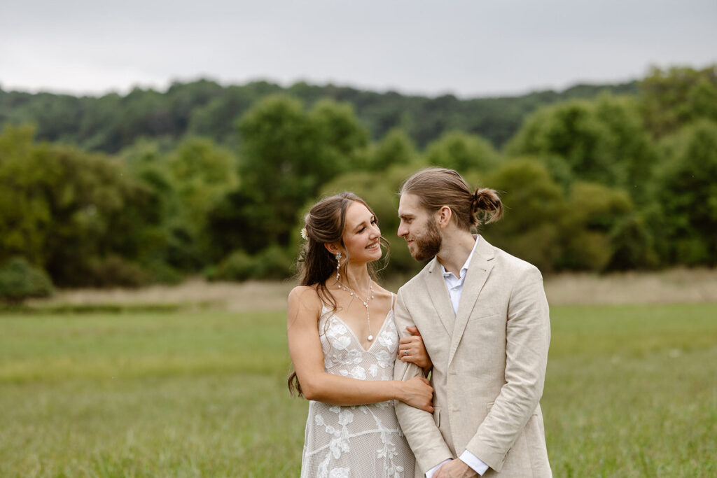 A couple standing arm in arm in a field 
