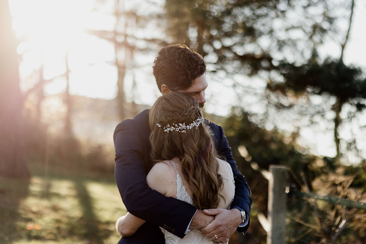 Newlyweds hugging tightly at sunset