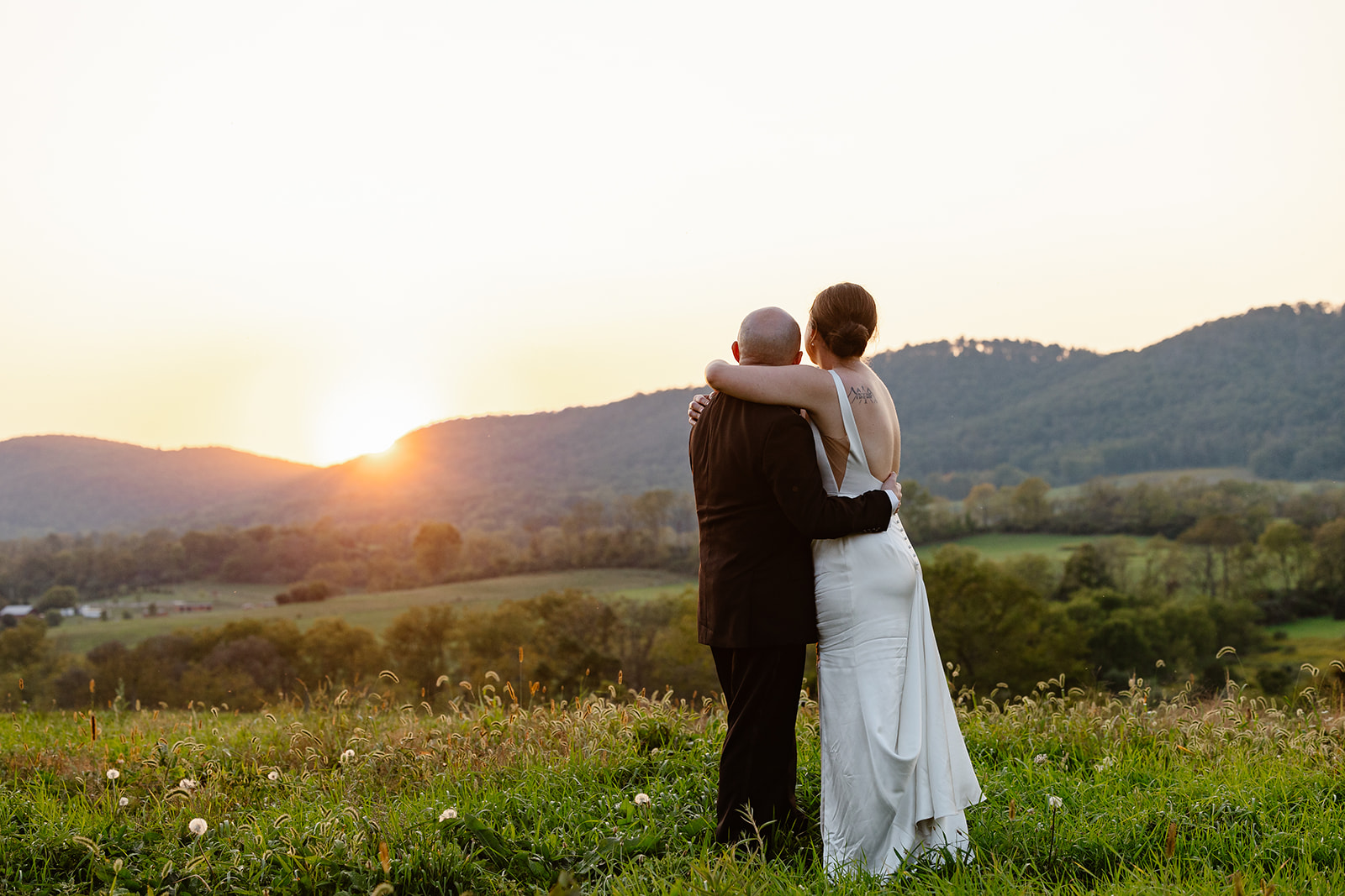 A bride and groom looking at the sun set over the mountains at RE Farm Cafe in State College, Pennsylvania