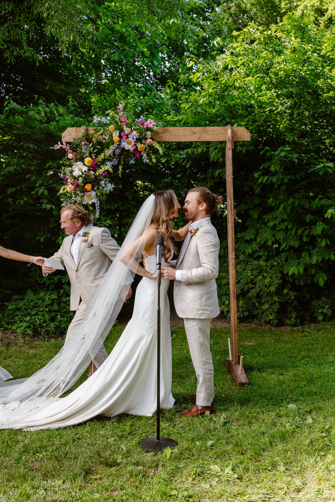 As a  bride and groom are about to kiss during their ceremony, a bridesmaid, yanks the officiant out of the frame