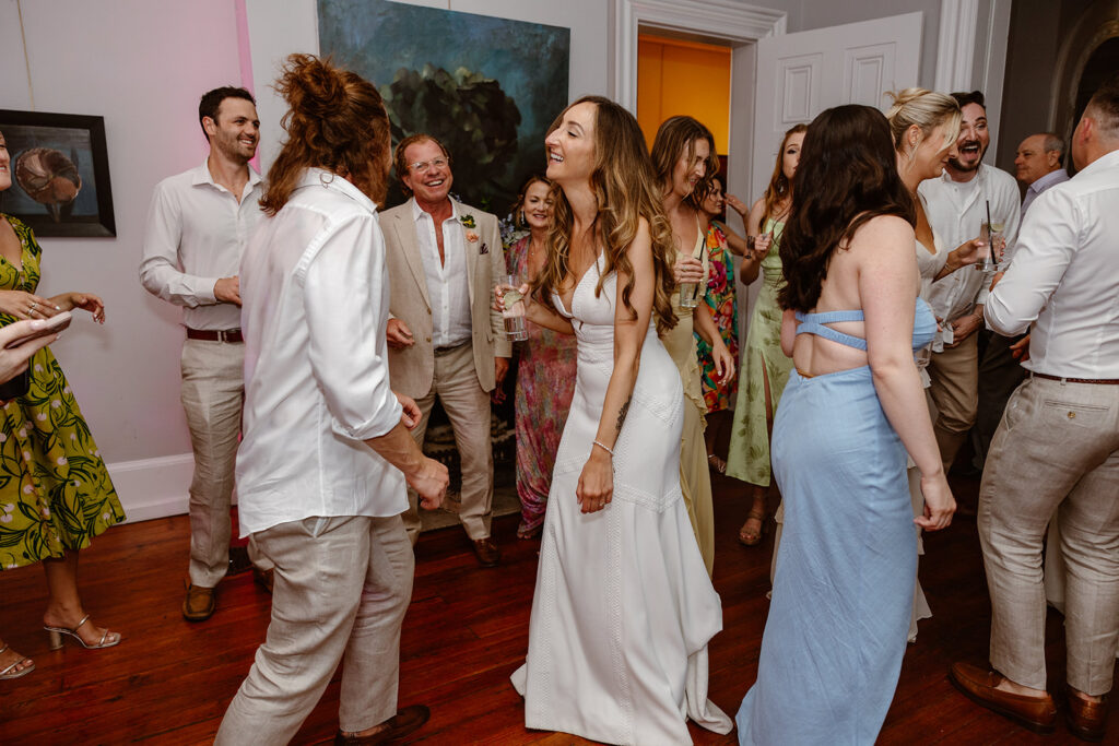 The bride and groom dancing during their reception. They are dancing in a gallery space with paintings on the wall