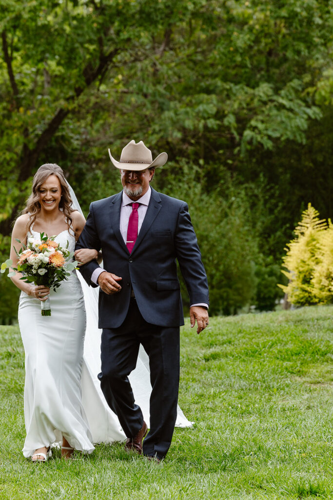 A dad walking the bride down the aisle. They are both smiling