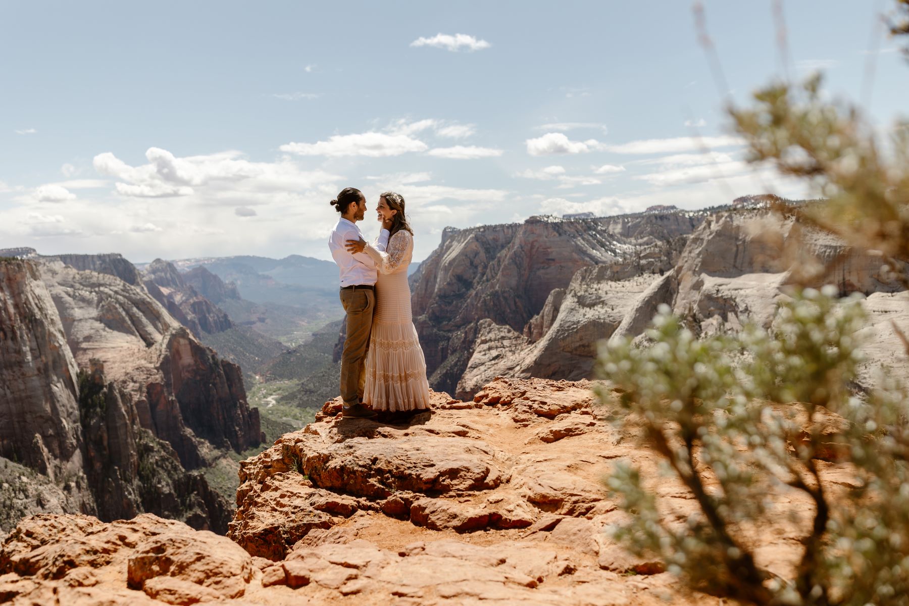 A bride and groom at Zion National Park during their elopement . The bride and groom are looking at one another, and the groom is gently caressing the brides cheek