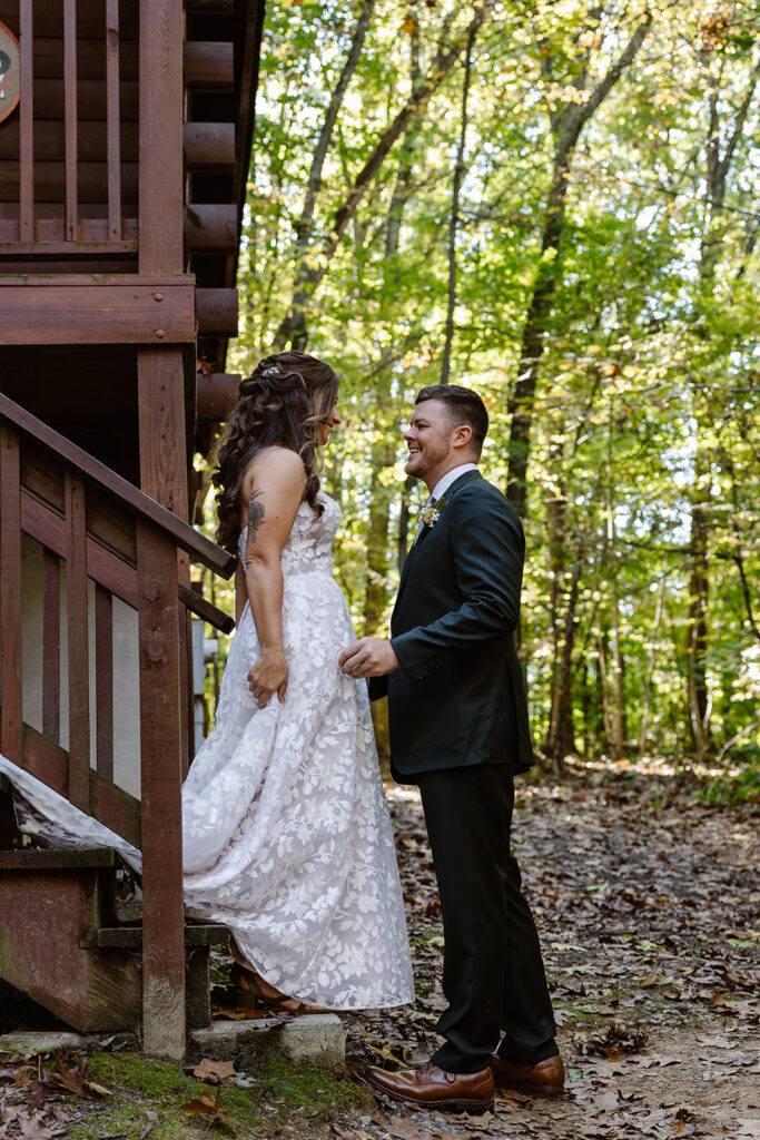 A bride and groom see each other for the first time on their wedding day. They are standing with their arms around each other, and the groom is smiling