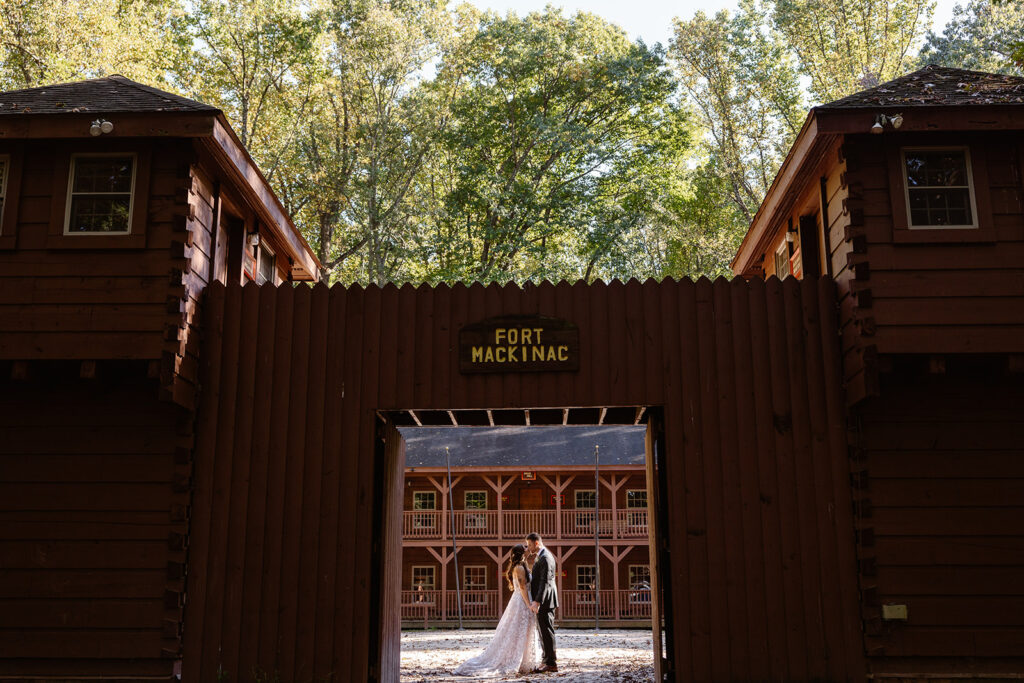 A bride and groom stand facing each other standing in a doorway at an old camp fort