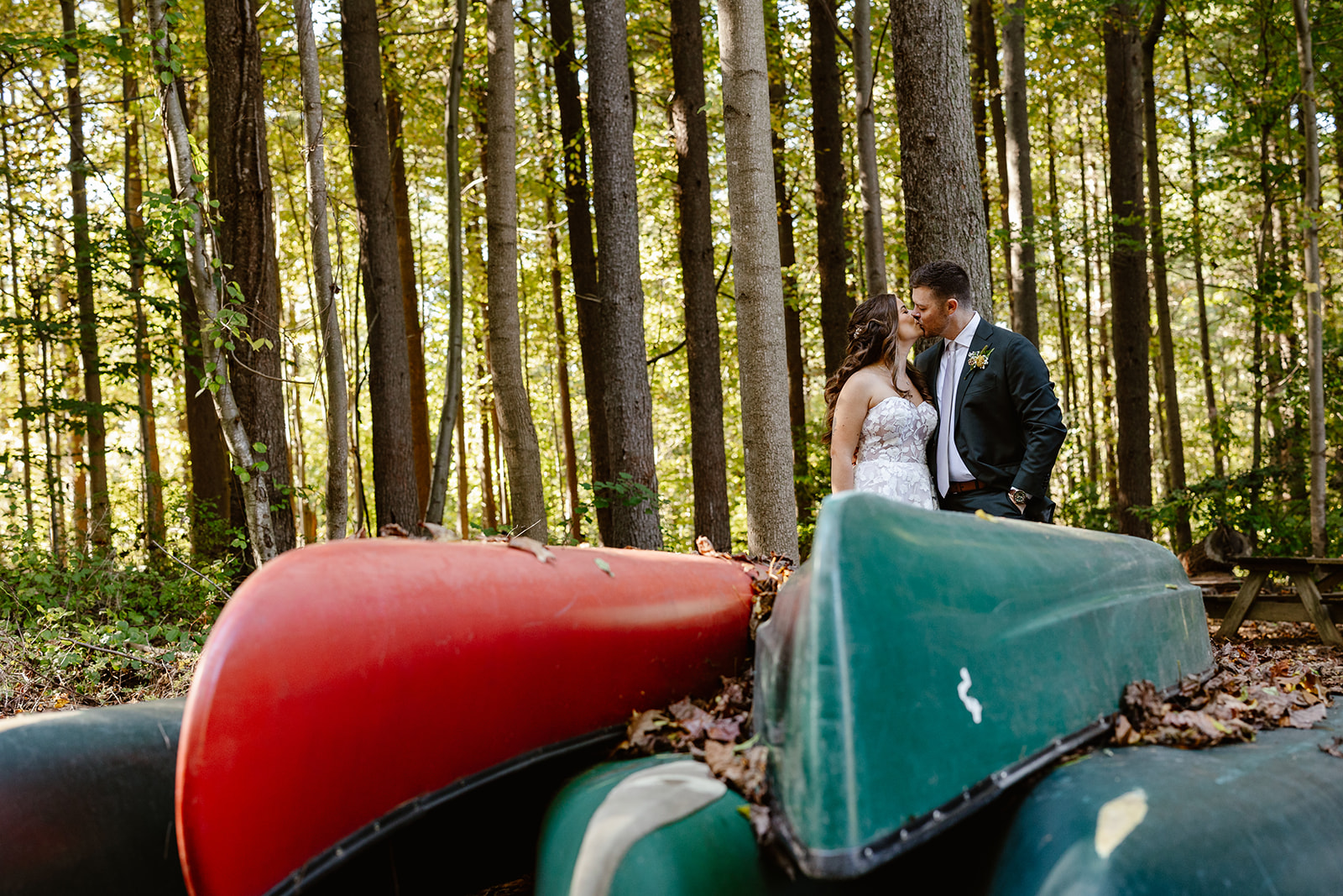 A couple stand in front of some colorful canoes on their wedding day.