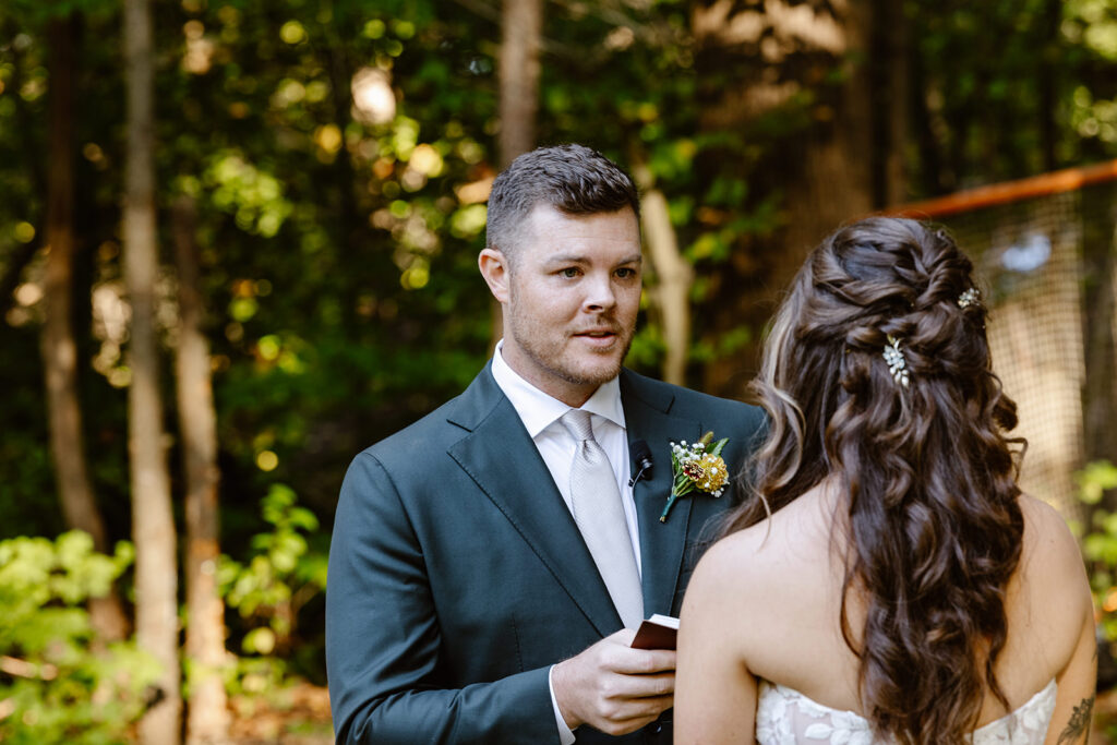 A groom looks serious as he reads his personal vows to his bride on their wedding day