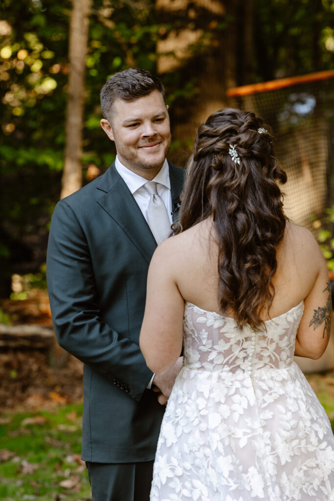 A groom looks at his bride lovingly as she reads her personal vows