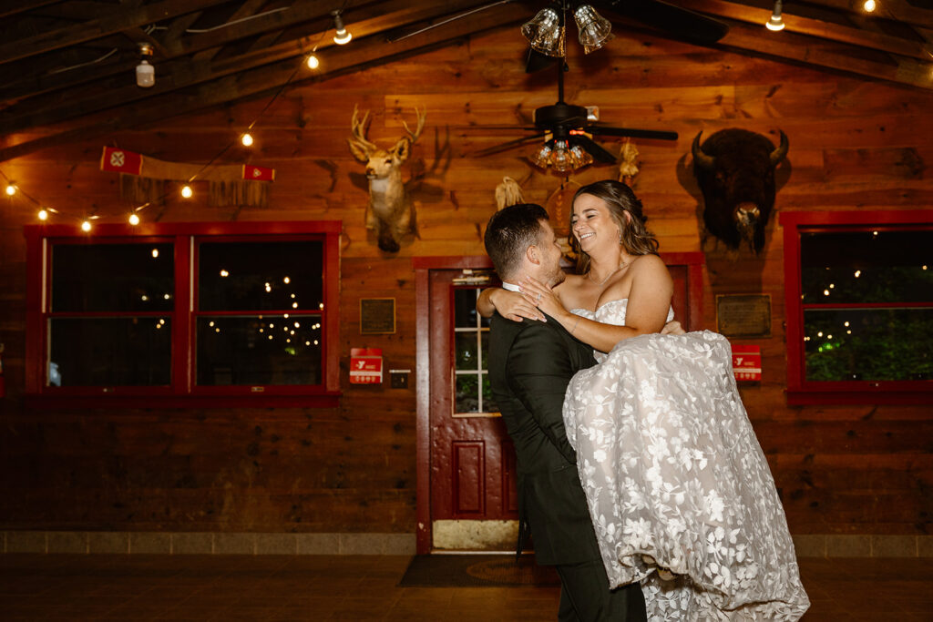 The groom picks up his bride and spins her around while they are dancing.