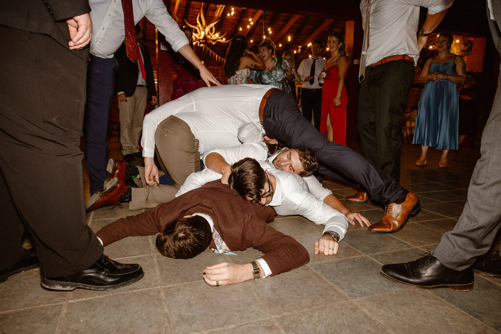 A groom and his friends all fall into a pile on the dance floor