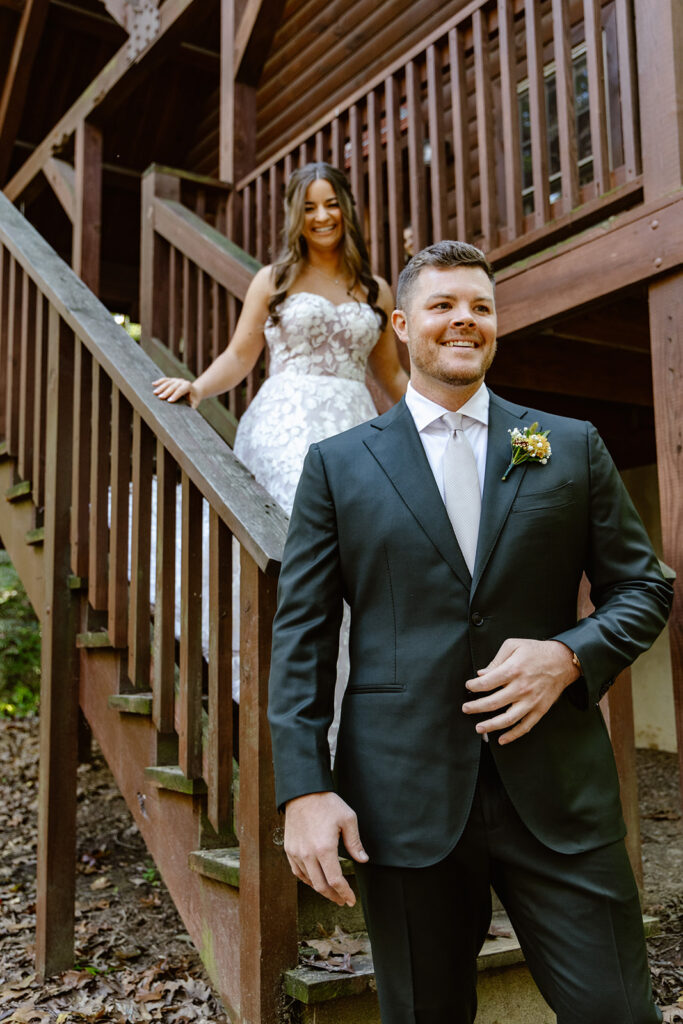 A bride and groom see each other for the first time on their wedding day. They are standing with their arms around each other, and the groom is smiling