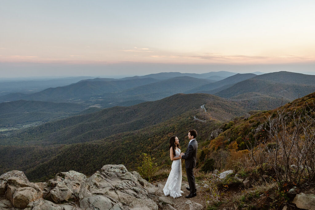 A bride and groom hold hands at a lookout at Shenandoah National Park