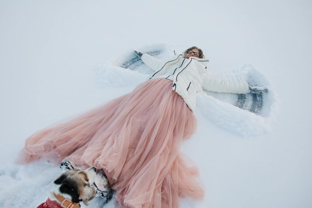 A bride makes a snow angel on the snow covered Lake Jean during her Rickett's Glenn Elopement in Pennsylvania.