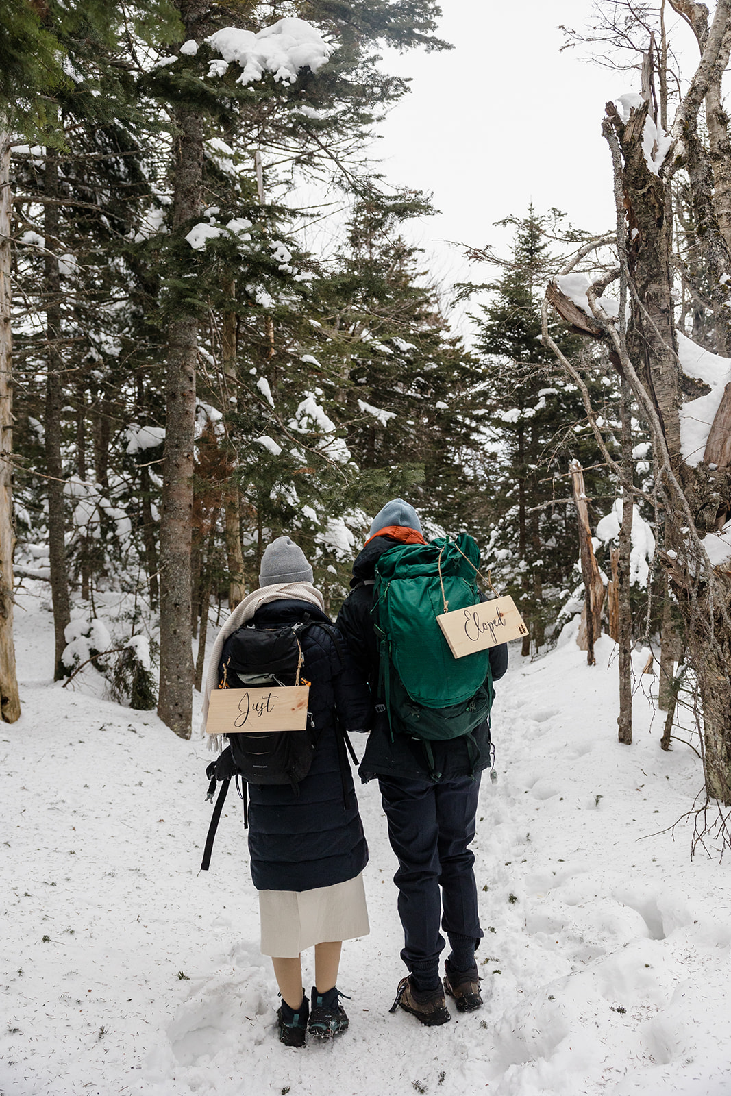 a couple trekking through the snow on the way to their elopement location