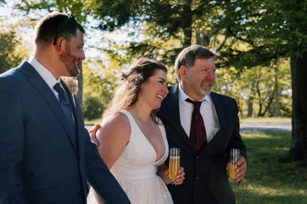 A bride leans into her dad while she listens to a speech by a family member during her elopement with family