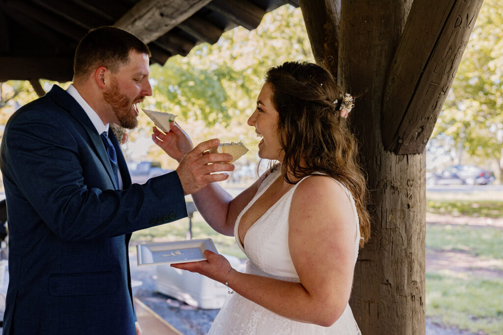 A bride and groom feed each other cake on their wedding day during a casual brunch