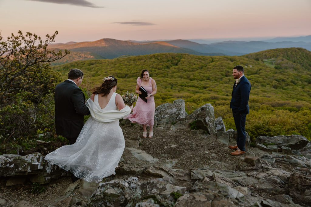 A groom watches as his bride and her father walking to the Summit of Stony Man