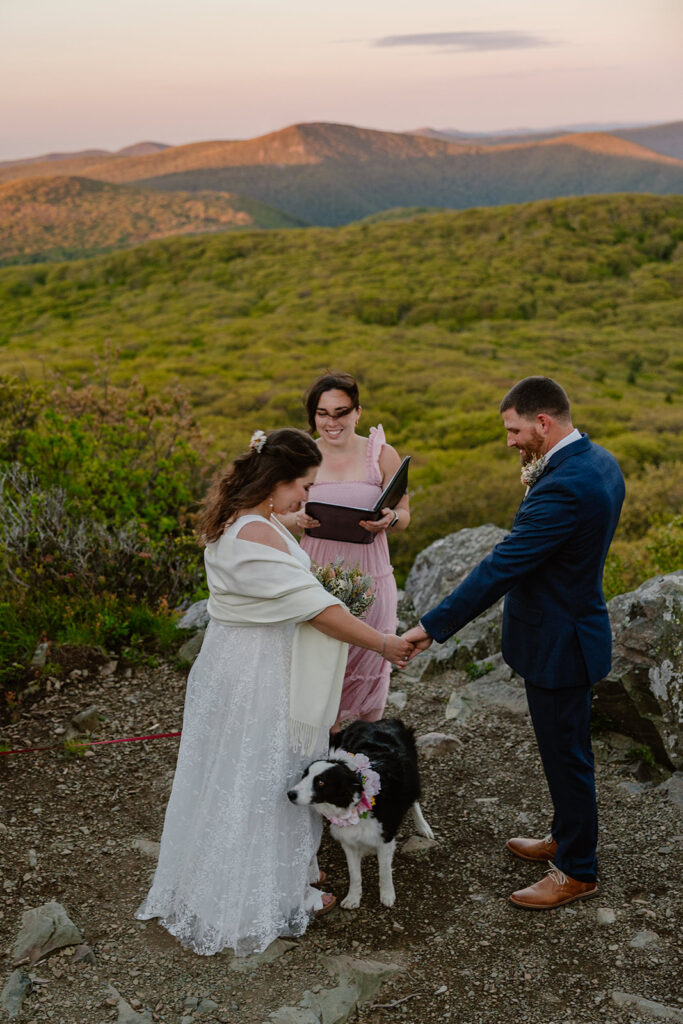 A bride and groom and their dog stand during their wedding ceremony